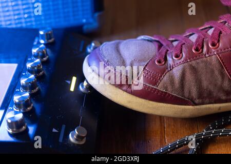 Il chitarrista preme i tasti del pedale della chitarra con il piede Foto Stock