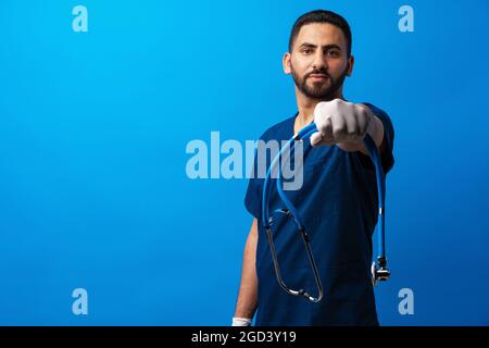 Giovane medico arabo maschile in piedi su sfondo blu Foto Stock