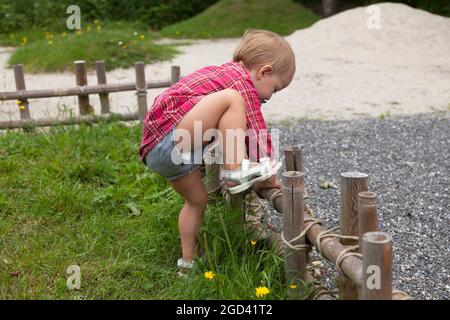 Umea, Norrland Svezia - 18 giugno 2021: La bambina sale sopra la bassa recinzione di bambù Foto Stock