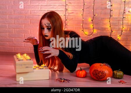Halloween zenzero donna strega con unghie lunghe e moda Halloween compongono. Garland sullo sfondo. Foto Stock