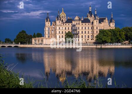 Schwerin, Germania. 10 agosto 2021. Le nuvole scure passano sopra il castello di Schwerin dopo una tempesta di tuoni. La sede del parlamento statale del Meclemburgo-Pomerania occidentale si riflette nel lago del castello. Credit: Jens Büttner/dpa-Zentralbild/dpa/Alamy Live News Foto Stock