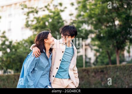 Carina coppia asiatica sorridente e guardandosi mentre camminano in città. Foto Stock