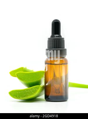 Olio essenziale di aloe vera con Aloe vera a fette. Immagine isolata su sfondo bianco, modello verticale. Spazio vuoto sulla bottiglia di colore marrone chiaro fo Foto Stock