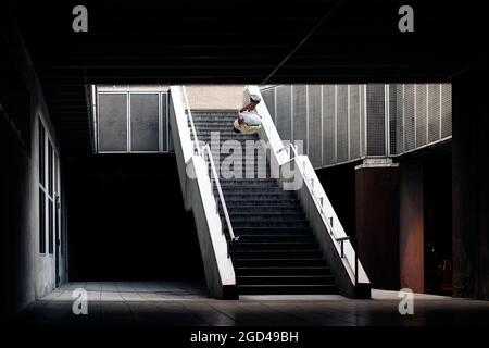 Giovane e simpatico che fa incredibili trucchi da parkour in città e si diverte. Foto Stock