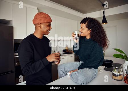 Coppia afroamericana bevendo caffè. Coppia mista che si guarda l'un l'altro in cucina a casa. Foto di alta qualità Foto Stock