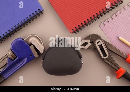 Costruzione di case, costruzione o proprietà concetto di vita still con un piatto di notebook, chiave, borsa e libri di nota in un tema blu e rosso Foto Stock