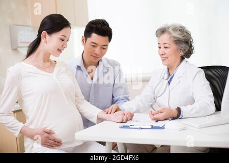 Il medico senior sente il polso della donna incinta Foto Stock