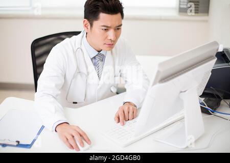 Giovane medico di sesso maschile che lavora in ufficio Foto Stock