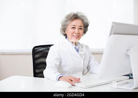 Dottoressa anziana che usa il computer in ufficio Foto Stock