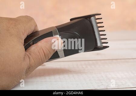 Rifinitore per capelli cordless. Durante la pandemia quando i barbershops sono chiusi, più uomini comprarono il dispositivo per tagliare i propri capelli. Punti di messa a fuoco selettivi. Sfocatura Foto Stock