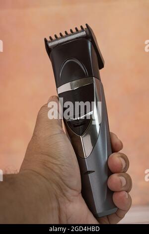 Rifinitore per capelli cordless. Durante la pandemia quando i barbershops sono chiusi, più uomini comprarono il dispositivo per tagliare i propri capelli. Punti di messa a fuoco selettivi. Sfocatura Foto Stock