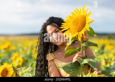 Ritratto di una bella donna sorridente dai capelli scuri con bouquet di girasoli Foto Stock