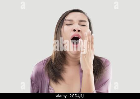 Donne asiatiche in sleepwear che brandisce su sfondo grigio, concetto di privazione del sonno di equilibrio di salute Foto Stock