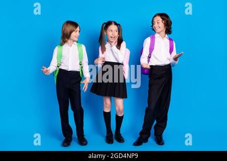 Foto di affascinanti zaini di formalwear per ragazzi che sorridono parlando guardandosi uno sfondo isolato di colore blu Foto Stock