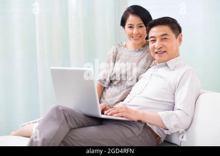 Felice coppia matura con il laptop a casa Foto Stock