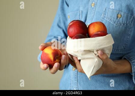 La ragazza tiene la borsa con frutti di pesca maturi Foto Stock