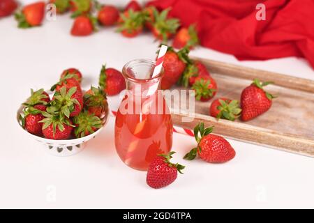 Limonata fatta in casa di frutti rossi di fragola in vaso circondata da frutti di bosco Foto Stock