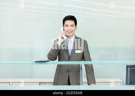 Uomo d'affari al telefono alla reception Foto Stock