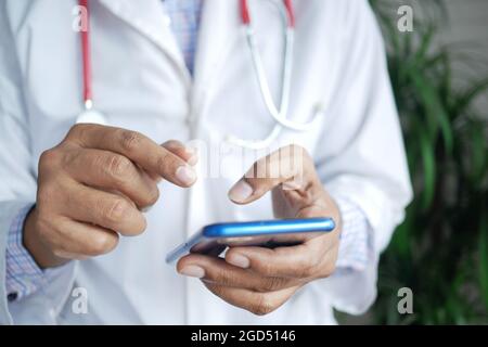 medico in camice bianco con uno smartphone. Foto Stock