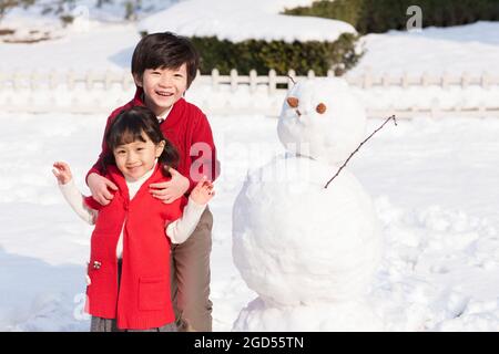 Bambini allegri con pupazzo di neve Foto Stock