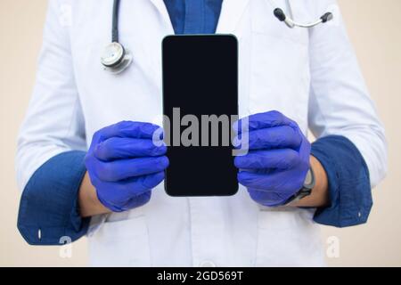 Sezione centrale di Doctor Holding telefono cellulare contro sfondo normale Foto Stock