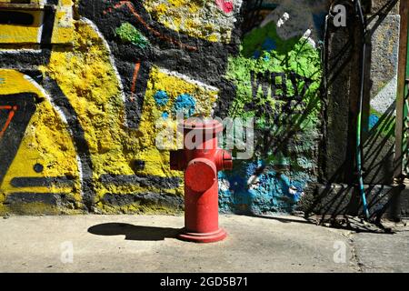 Idrante fuoco rosso contro un muro di graffiti a Santa Teresa, Rio de Janeiro, Brasile. Foto Stock