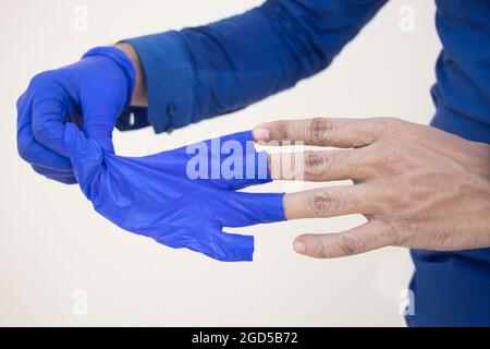 Primo piano Doctor che rimuove i guanti dalla mano Foto Stock