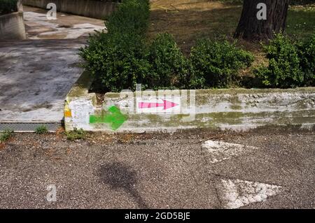 Le frecce direzionali colorate e tracciate sul muro indicano la strada pedonale (Marche, Italia, Europa) Foto Stock