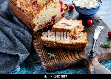 Primo piano con vista su un pane al rosmarino di mirtillo con fette di fronte e formaggio spalmato dietro. Foto Stock