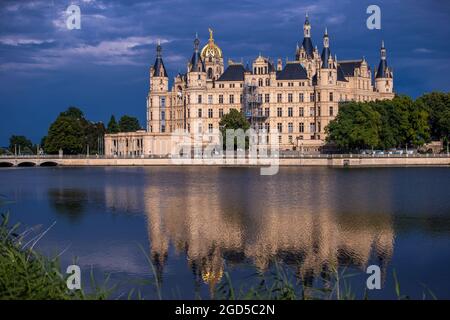 Schwerin, Germania. 10 agosto 2021. Le nuvole scure passano sopra il castello di Schwerin dopo una tempesta di tuoni. La sede del parlamento statale del Meclemburgo-Pomerania occidentale si riflette nel lago del castello. Credit: Jens Büttner/dpa-Zentralbild/ZB/dpa/Alamy Live News Foto Stock