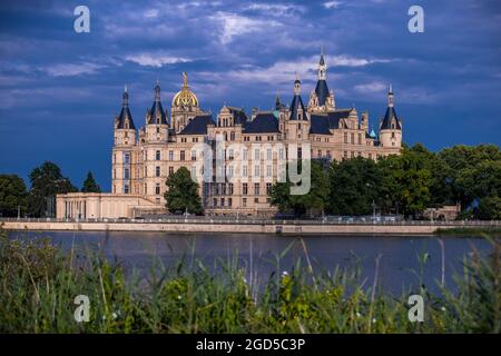 Schwerin, Germania. 10 agosto 2021. Le nuvole scure passano sopra il castello di Schwerin dopo una tempesta di tuoni. La sede del parlamento statale del Meclemburgo-Pomerania occidentale si riflette nel lago del castello. Credit: Jens Büttner/dpa-Zentralbild/ZB/dpa/Alamy Live News Foto Stock