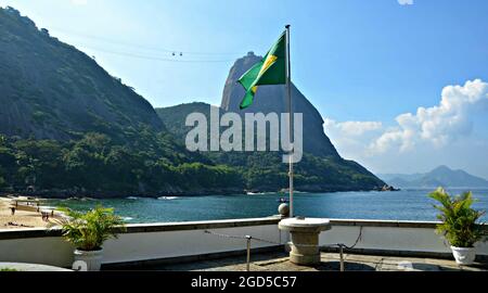 Vista panoramica del Pan di zucchero e la tessitura bandiera brasiliana come visto da Praia Vermelha nel quartiere di Urca, Rio de Janeiro Brasile.. Foto Stock