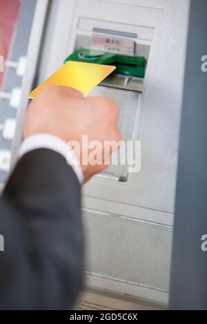 Uomo d'affari che utilizza una macchina automatica per il bancomat con carta di credito Foto Stock