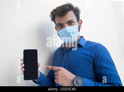 Giovane bell'uomo che punta al suo cellulare in mano Foto Stock