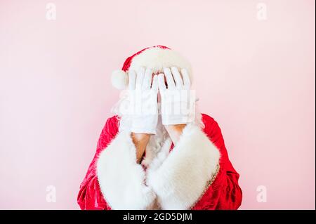 Uomo vestito come Babbo Natale che ricopre il viso con le mani Foto Stock