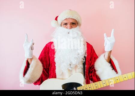 Uomo vestito da euforico Babbo Natale con chitarra elettrica Foto Stock