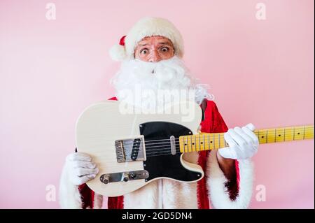 Uomo vestito da euforico Babbo Natale con chitarra elettrica Foto Stock