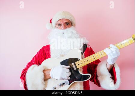 Uomo vestito da Babbo Natale che suona la chitarra elettrica Foto Stock