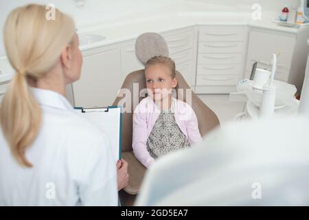 Piccola ragazza bionda che ha un appuntamento con la pediadontis Foto Stock