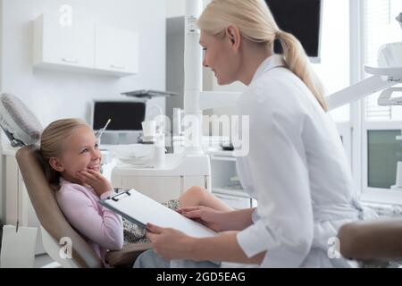 Piccola ragazza bionda che ha un appuntamento con la pediadontis Foto Stock