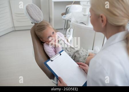 Piccola ragazza bionda che ha un appuntamento con la pediadontis Foto Stock