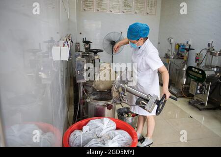 Zhangjiajie, provincia di Hunan in Cina. 11 Agosto 2021. Un farmacista toglie il residuo dopo aver fatto le tradizionali decezioni di medicina cinese (TCM) in un ospedale di TCM a Zhangjiajie, provincia di Hunan della Cina centrale, 11 agosto 2021. Oltre 12,000 dosi di decotti TCM vengono effettuate dall'ospedale ogni giorno per aiutare a controllare il recente picco di infezioni COVID-19 in Zhangjiajie. Credit: Chen Sihan/Xinhua/Alamy Live News Foto Stock