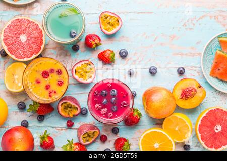 Variazione di frullati e bevande rinfrescanti con frutta fresca per l'estate calda su sfondo blu Foto Stock