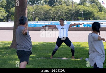 Un istruttore di yoga e benessere di mezza età insegna agli studenti in una lezione al Flushing Meadows Corona Park in Queens. Foto Stock
