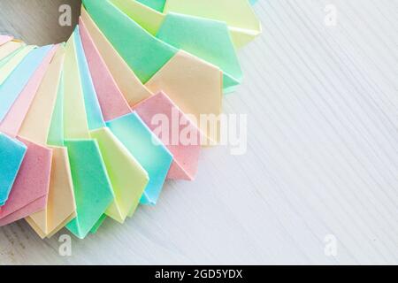 L'anello Origami, struttura parametrica astratta fatta di fogli di carta colorati, si trova su una scrivania di legno bianco, vista dall'alto Foto Stock