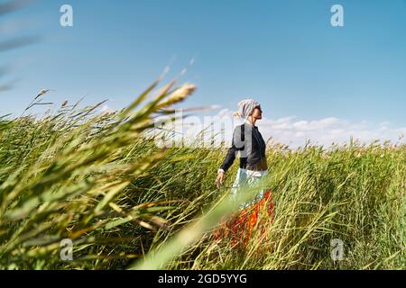 donna asiatica che gode di aria fresca e luce solare in un campo di canne Foto Stock