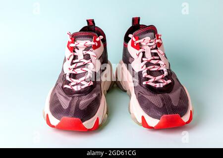 Sneaker sportive da donna alla moda, nere con dettagli rossi su sfondo blu. Nuove scarpe da gioventù per ragazze. Vista frontale. Foto Stock