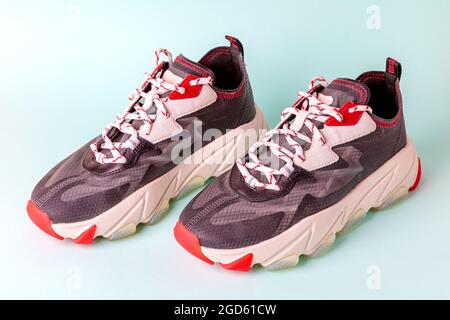 Sneaker sportive da donna alla moda, nere con dettagli rossi su sfondo blu. Nuove scarpe da gioventù per ragazze. Vista frontale. Foto Stock