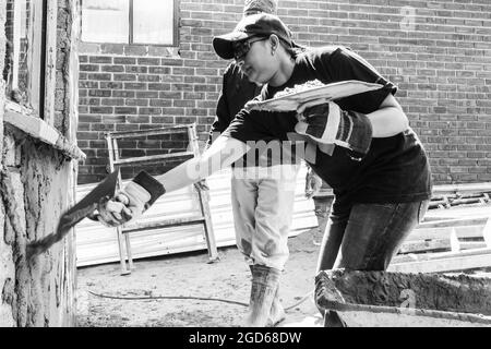 JOHANNESBURG, SUD AFRICA - 06 gennaio 2021: Una scala di grigi di persone in un programma di azione comunitaria che aiuta a costruire una piccola casa Foto Stock