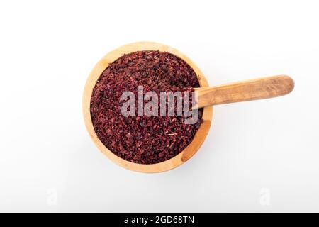 Sumac. Spezia Sumac in ciotola di legno, su sfondo bianco. Sumac, fiocchi di sumac. Macro shot sumac. Foto Stock